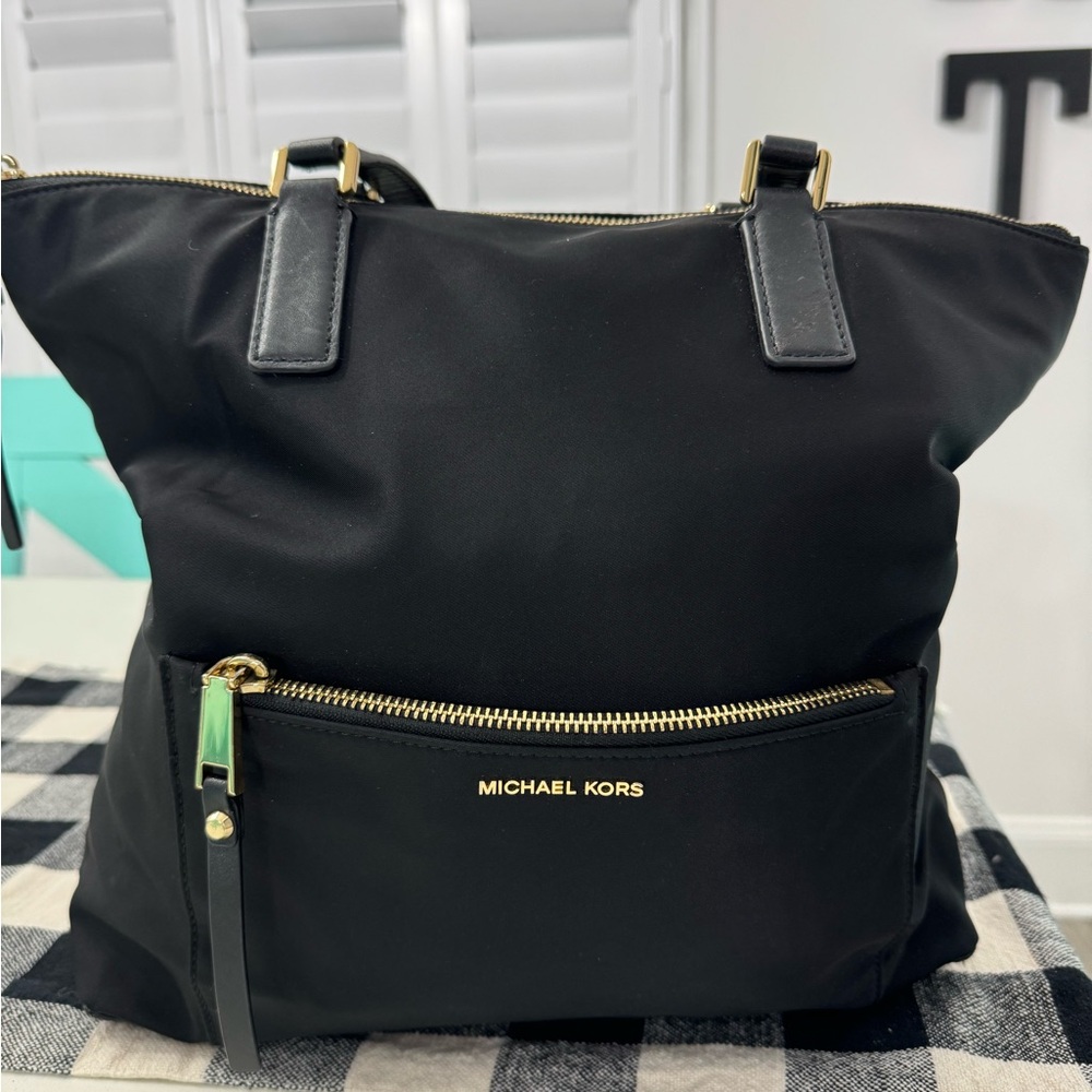 Michael Kors black,  gold accent handbag; minor wear on a strap (pictured).